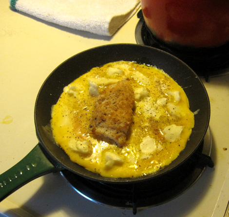 I plopped a hunk of leftover fish in the center and poured the eggs around it. Those white blobby things are bits of Spring Hill Farms fresh curd cheese.